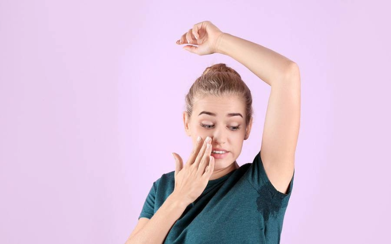 Woman with excessive underarm sweating visible on his shirt