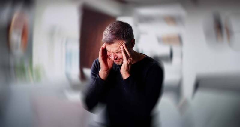 Photo of a person holding their head and appearing dizzy, surrounded by visual sound wave effects to illustrate sensitivity to noise during dizziness
