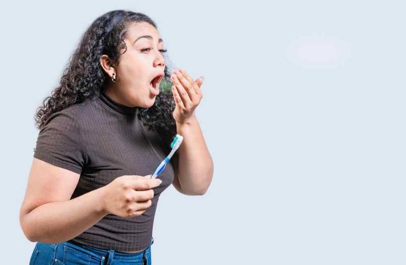 Close-up photo of a female covering her mouth, illustrating bad breath (halitosis) and its impact on confidence and social interactions