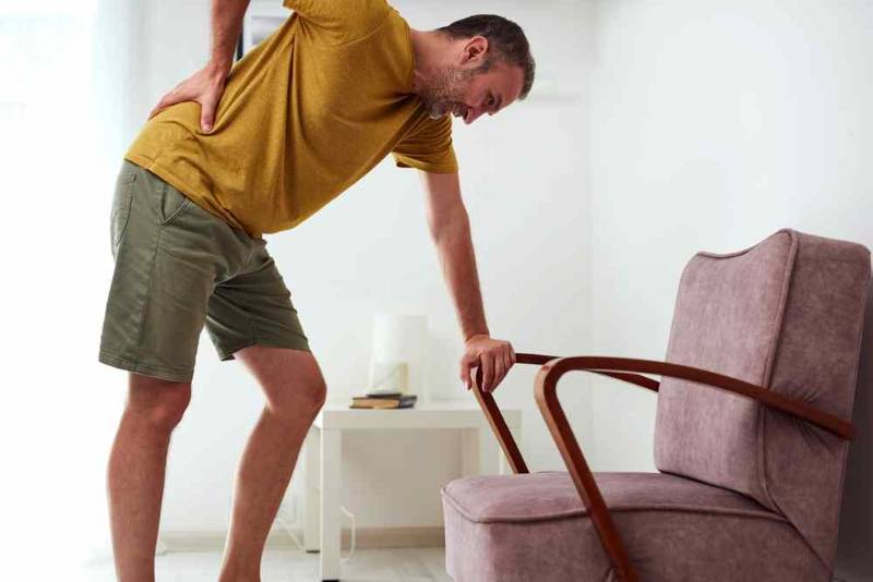 Person holding their lower back in pain, illustrating sciatica and nerve-related leg discomfort