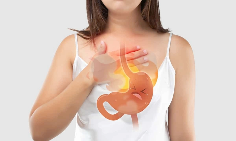 Illustration of a woman holding her upper abdomen, showing discomfort from heartburn and acid reflux