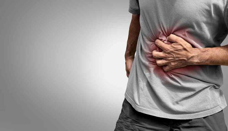 A man clutching his abdomen in discomfort due to colitis, showing signs of digestive pain and distress