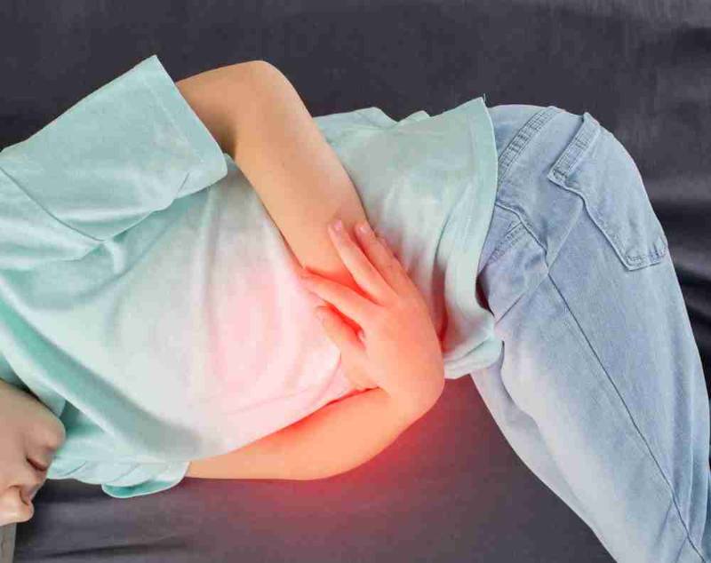 A patient holding their abdomen in pain due to Irritable Bowel Syndrome (IBS) symptoms