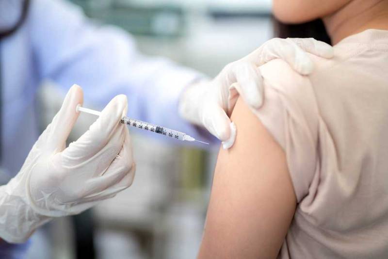 A doctor administering a flu vaccine to an adult patient, with a close-up of the injection in the upper arm, emphasizing seasonal flu protection and preventive healthcare
