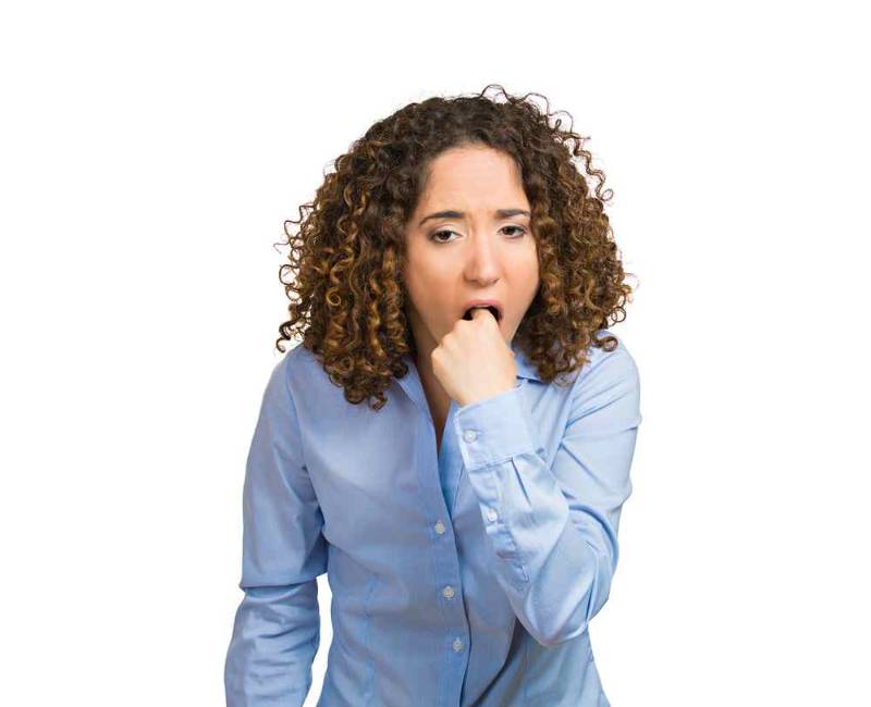 A young woman inserting her finger into her throat in an attempt to induce vomiting, illustrating the harmful behaviors associated with anorexia nervosa