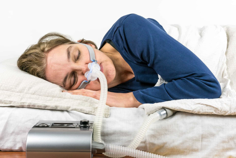 A woman sleeping fitfully with interrupted breathing, illustrating the symptoms of sleep apnea.