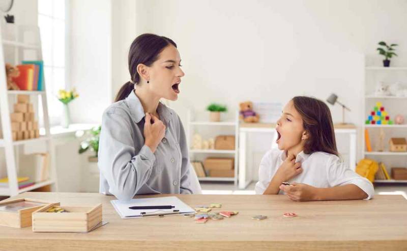 A young girl with stuttering disorder speaking to her instructor, showing signs of hesitation and nervousness as she tries to express herself